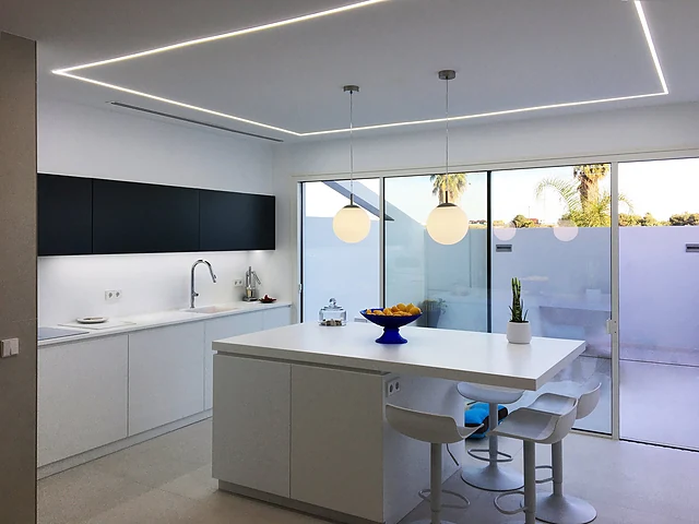 Cocina con isla y ventanal a la terraza de la Casa JUMA en Pinedo, reforma de Grupo Remodela